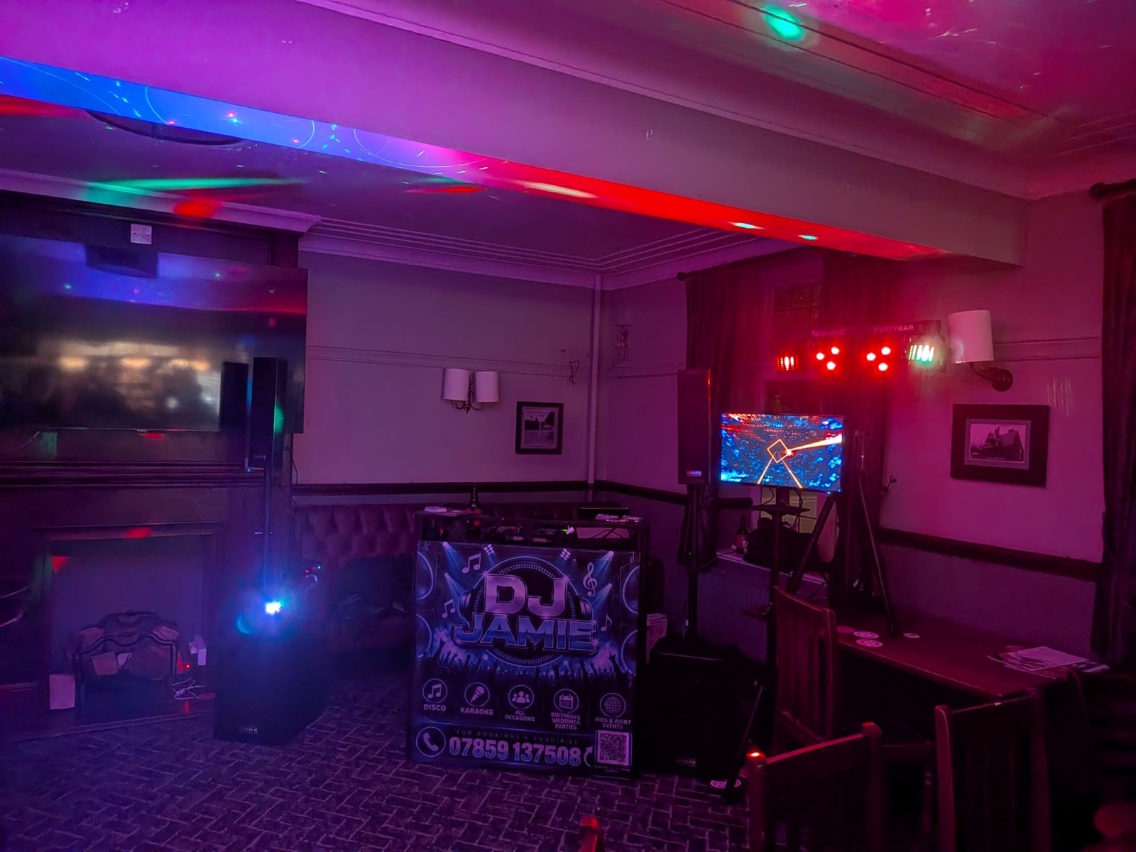 Function room lit in purple and red with the DJ Jamie booth